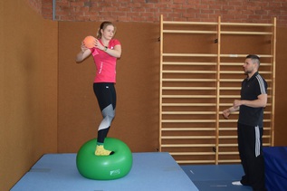 Wasserspringerin steht auf Gymnastikball und hält kleineren Ball in der Hand (verweist auf: Von der Grundlagenforschung in die Anwendung)